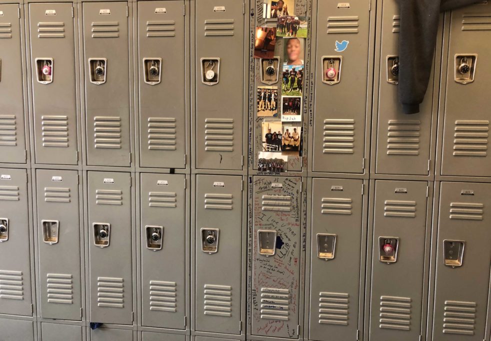 Row of lockers, with one locker covered in photos and hand-written messages.