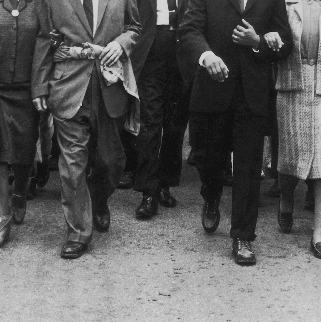 A black and white photograph of men in suits walking