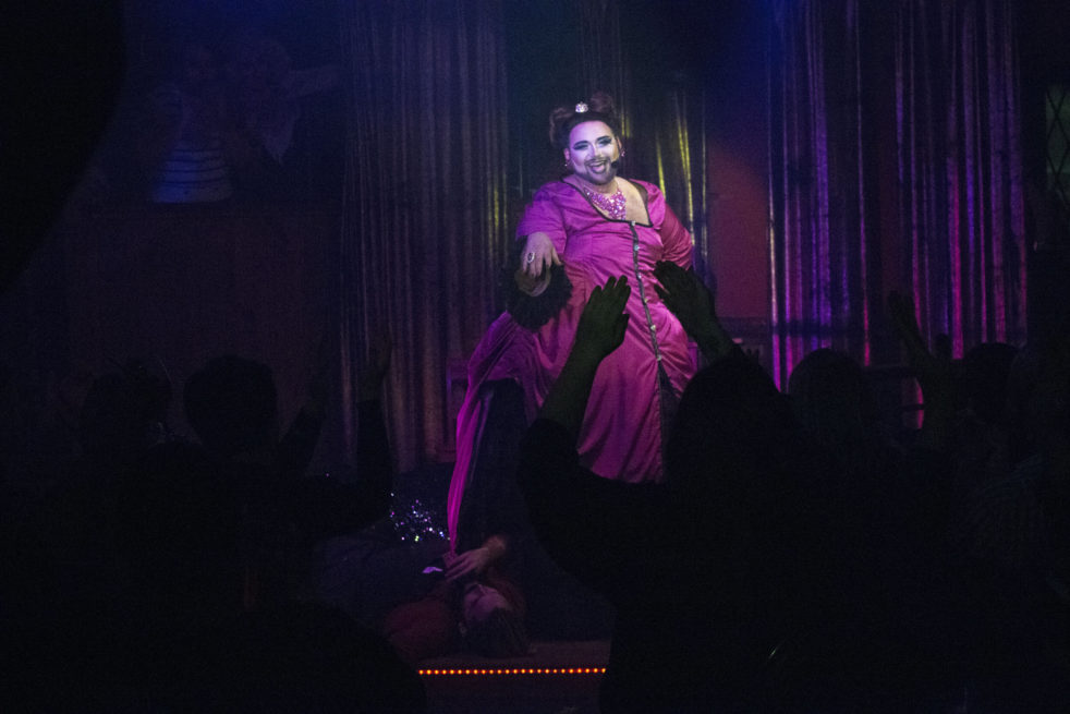 The drag performer Eric Jaffe performing on stage in front of a crowd.