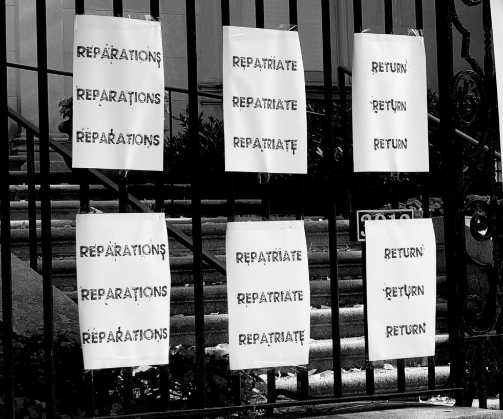 A series of starkly simple posters taped onto an iron gate, with bold text designs highlighting the words Reparations, Repatriate, Return.