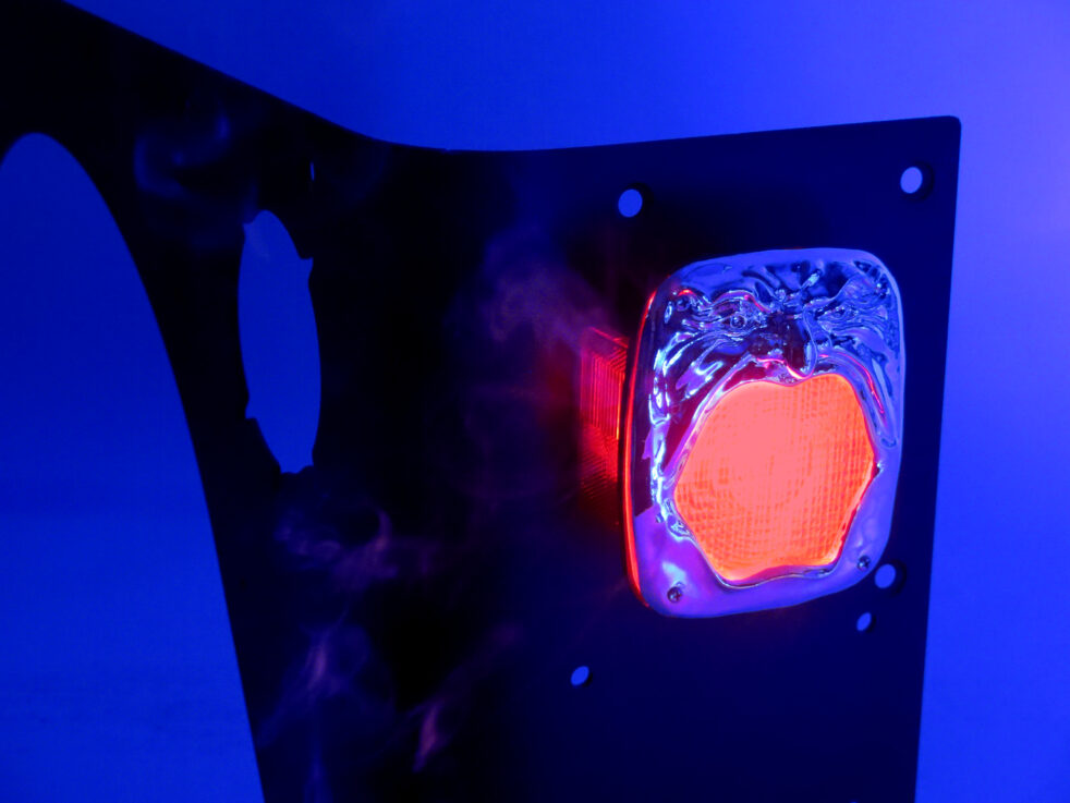 Sculpture that depicts a face with red light shining from the mouth, against a blue background.