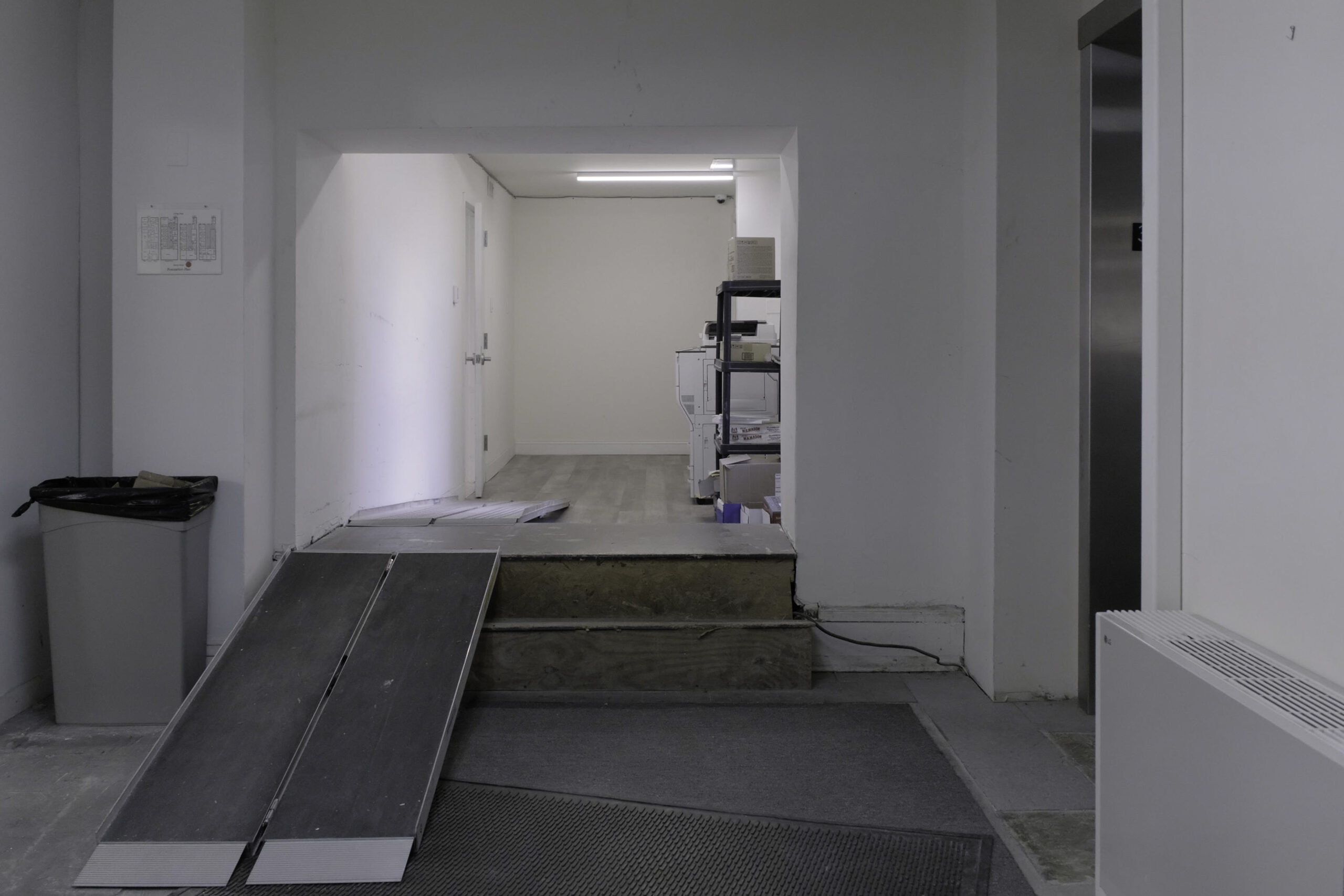 An interior space with signs of construction and shelving and a printer in the background.