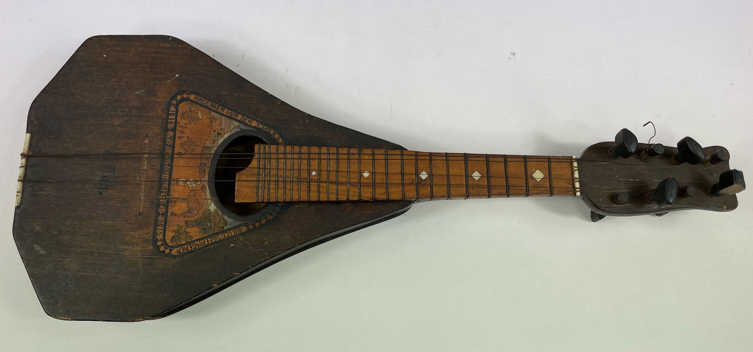 A vintage mandolin with a triangular body and ornate inlay designs.